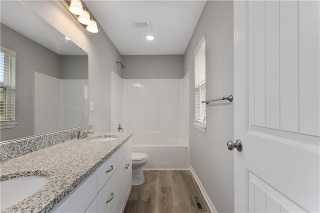 full bathroom with vanity, hardwood / wood-style floors, toilet, and washtub / shower combination