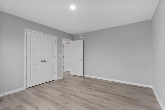 unfurnished bedroom with light hardwood / wood-style flooring and a closet