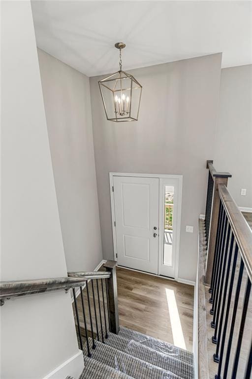 entrance foyer with a chandelier, a high ceiling, wood finished floors, baseboards, and stairway