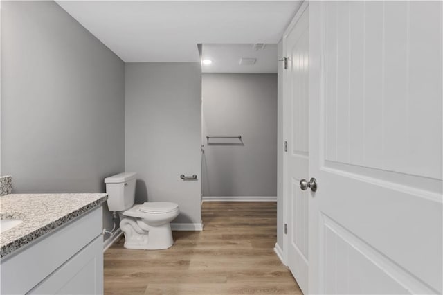 bathroom with toilet, wood finished floors, vanity, and baseboards