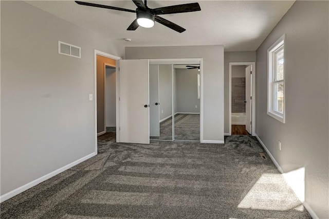 unfurnished bedroom featuring ceiling fan, a closet, and dark colored carpet