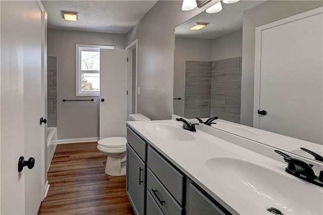 full bathroom featuring hardwood / wood-style flooring, vanity, a textured ceiling, bathtub / shower combination, and toilet