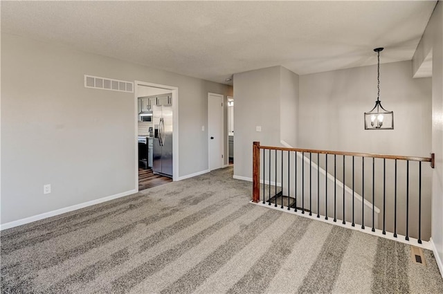 carpeted empty room featuring a notable chandelier