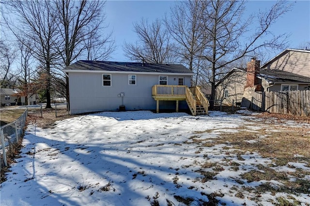 snow covered rear of property with a deck