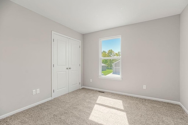 unfurnished bedroom featuring a closet, carpet flooring, visible vents, and baseboards