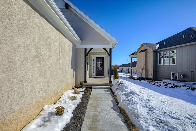 view of snowy exterior with stucco siding