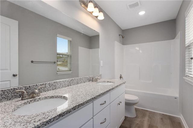 full bathroom with hardwood / wood-style flooring, shower / tub combination, vanity, and toilet