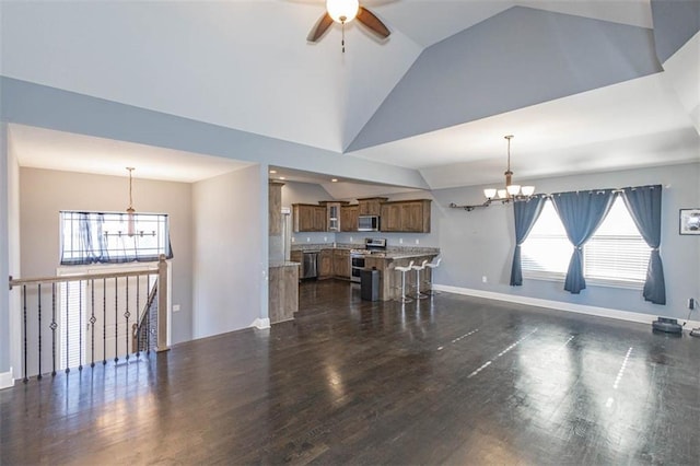 living room with vaulted ceiling, ceiling fan with notable chandelier, and dark hardwood / wood-style flooring