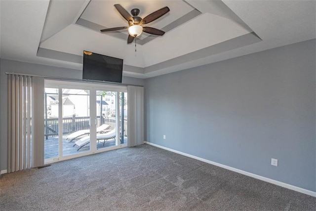 unfurnished room with ceiling fan, a raised ceiling, and carpet