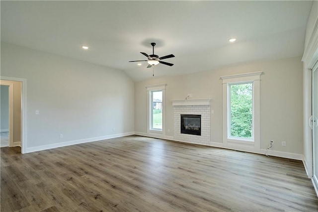 unfurnished living room featuring lofted ceiling, a fireplace, light hardwood / wood-style floors, and ceiling fan