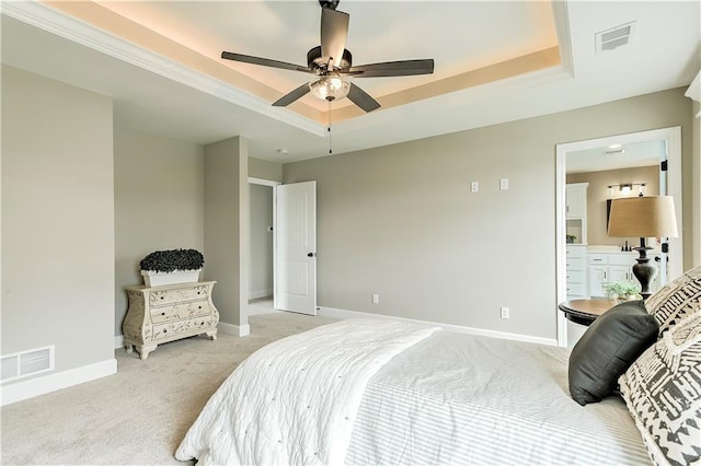 carpeted bedroom with ceiling fan, ensuite bath, and a tray ceiling