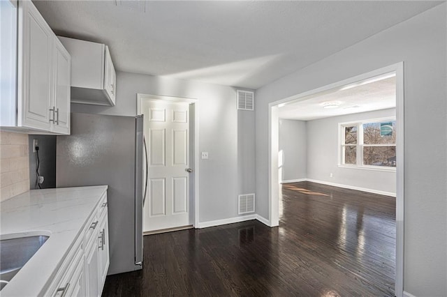 kitchen featuring sink, stainless steel refrigerator, light stone countertops, white cabinets, and dark hardwood / wood-style flooring