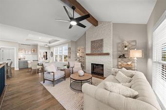 living room with hardwood / wood-style flooring, a large fireplace, a healthy amount of sunlight, and lofted ceiling with beams