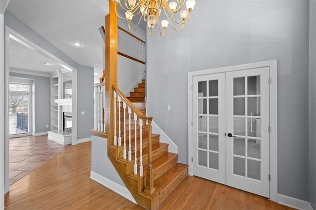 staircase with hardwood / wood-style floors, built in features, a fireplace, and french doors