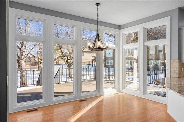 doorway to outside featuring wood-type flooring and a notable chandelier