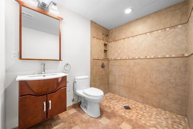 bathroom with vanity, a tile shower, and toilet