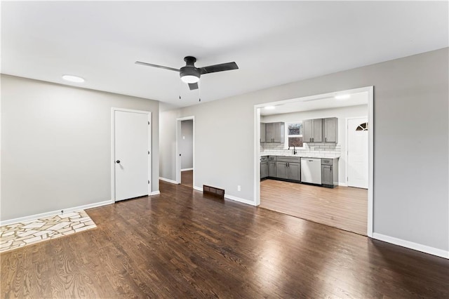 unfurnished living room featuring ceiling fan, dark hardwood / wood-style floors, and sink