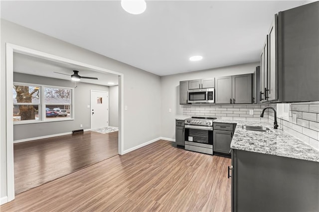 kitchen featuring light stone counters, appliances with stainless steel finishes, sink, and gray cabinetry