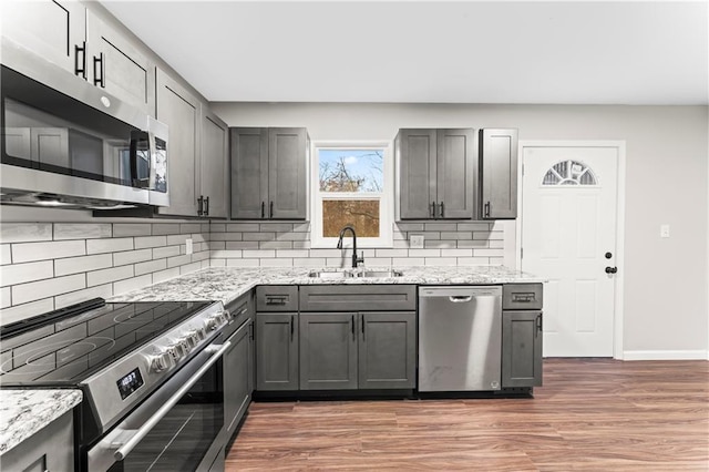 kitchen featuring gray cabinetry, sink, light stone countertops, and appliances with stainless steel finishes