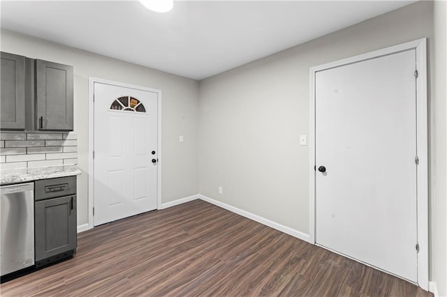 interior space with gray cabinetry, stainless steel dishwasher, dark hardwood / wood-style flooring, light stone countertops, and backsplash