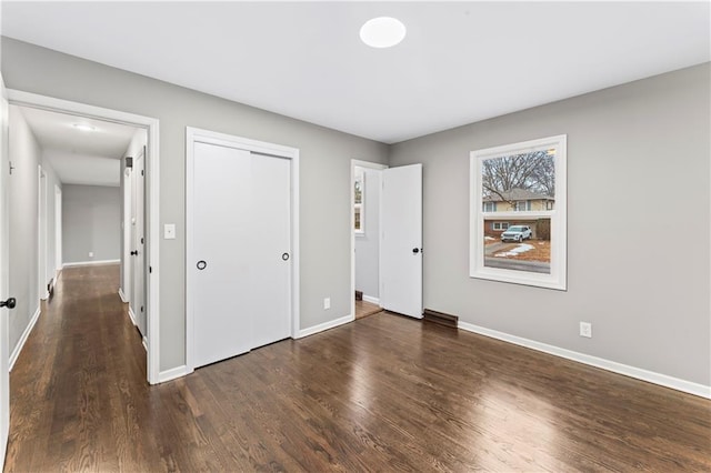 unfurnished bedroom with dark hardwood / wood-style flooring and a closet