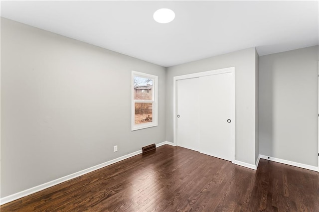 unfurnished bedroom featuring dark hardwood / wood-style flooring and a closet