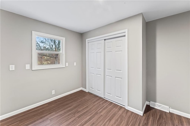 unfurnished bedroom featuring a closet and dark hardwood / wood-style floors