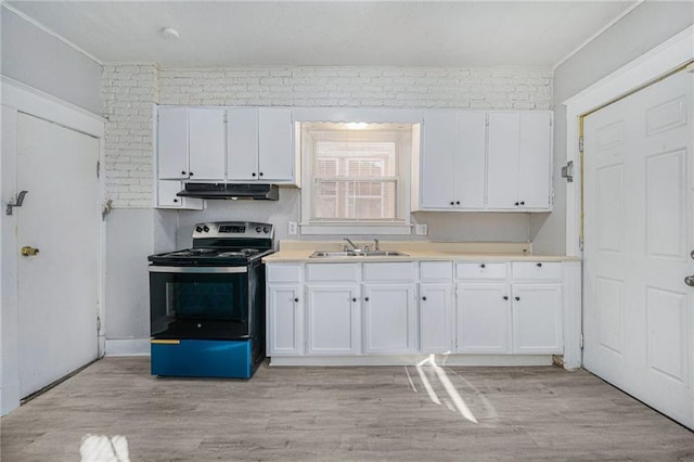 kitchen featuring white cabinets, brick wall, sink, and electric range