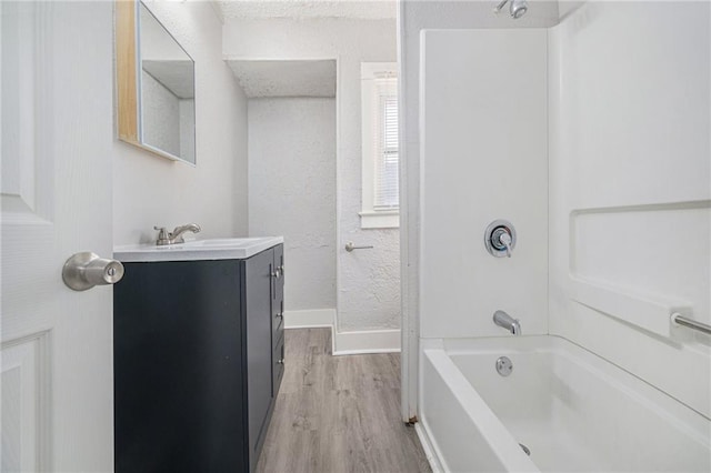 2463 Denver Ave, Kansas City, MO 64127 - bathroom featuring wood finished floors, vanity, and washtub / shower combination