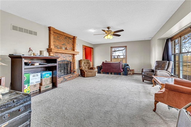 living room featuring ceiling fan, plenty of natural light, a fireplace, and a textured ceiling