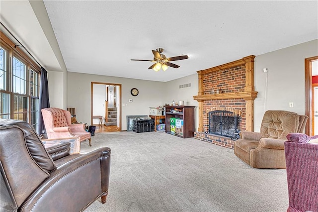 carpeted living room with a brick fireplace and ceiling fan