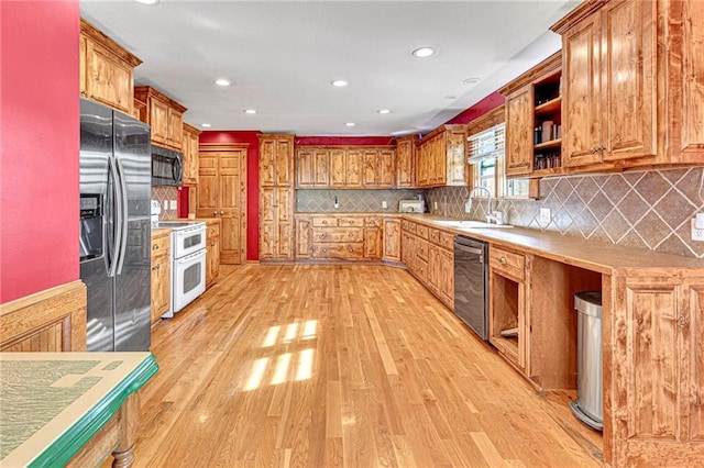 kitchen featuring appliances with stainless steel finishes, sink, light hardwood / wood-style floors, and decorative backsplash