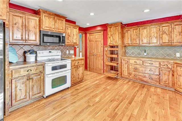 kitchen with double oven range, decorative backsplash, and light wood-type flooring