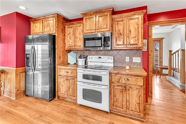 kitchen featuring decorative backsplash, stainless steel appliances, and light wood-type flooring