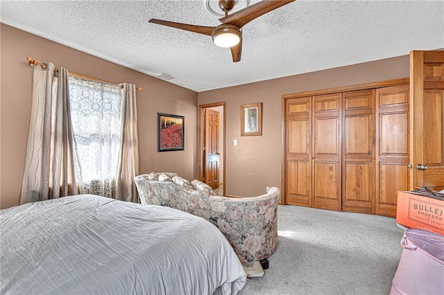 carpeted bedroom featuring ceiling fan and a textured ceiling