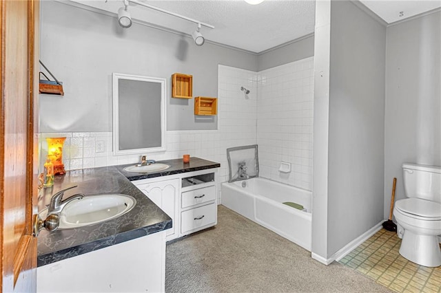 full bathroom with tiled shower / bath, vanity, toilet, and a textured ceiling