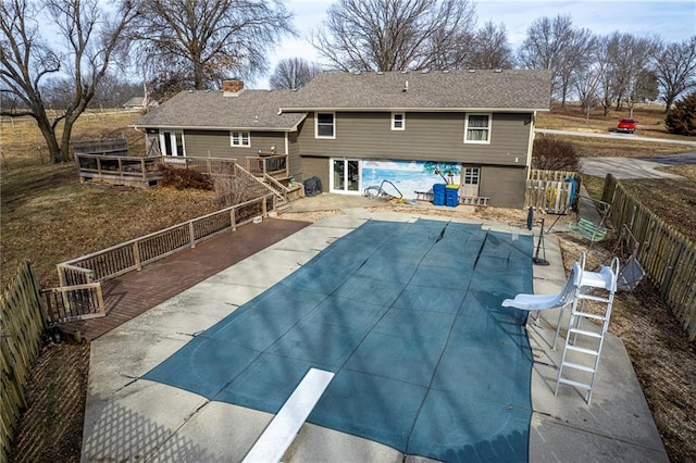 view of pool with a wooden deck, a diving board, and a patio area