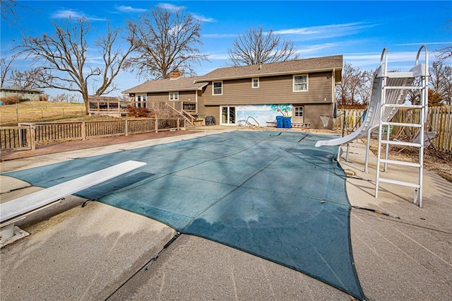 view of swimming pool featuring a patio area, a diving board, and a water slide