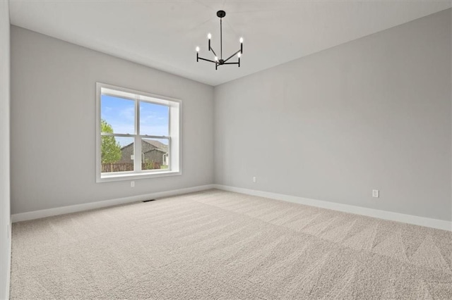 unfurnished room featuring a notable chandelier and light colored carpet