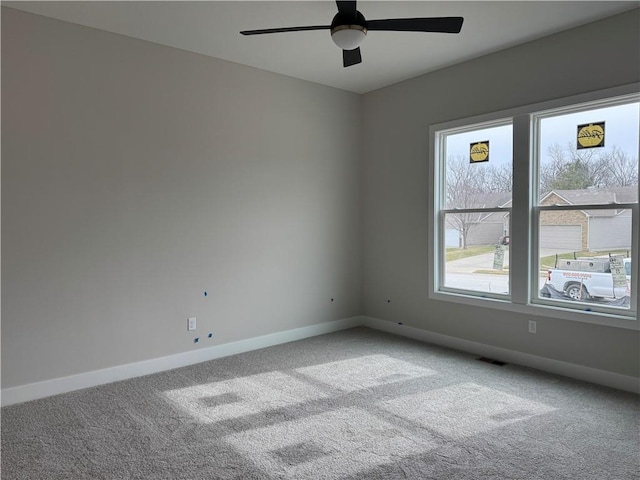 carpeted empty room with visible vents, ceiling fan, and baseboards