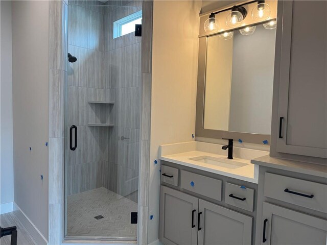 full bathroom featuring a stall shower, vanity, and baseboards