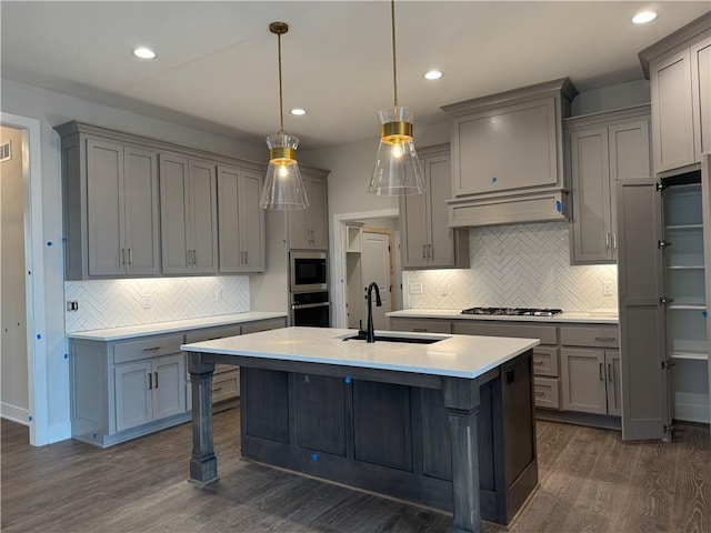 kitchen with appliances with stainless steel finishes, light countertops, a sink, and gray cabinetry