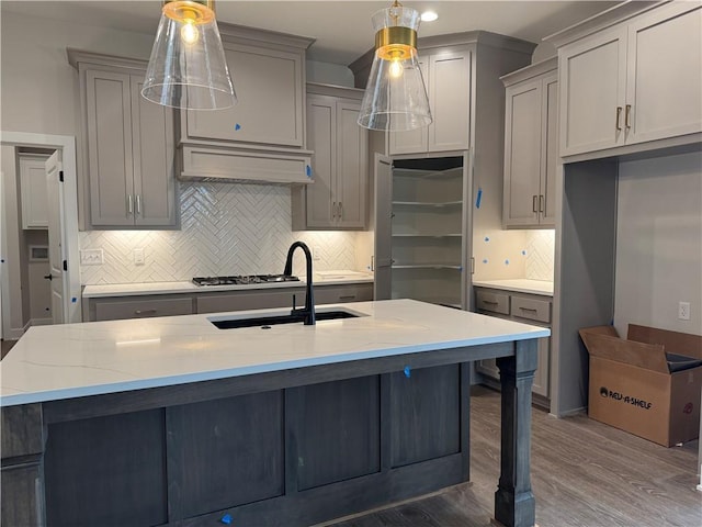 kitchen featuring tasteful backsplash, gray cabinets, appliances with stainless steel finishes, a sink, and light stone countertops