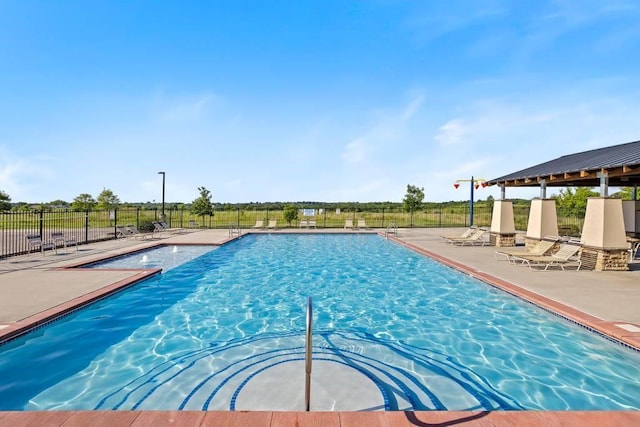 community pool with a patio area and fence