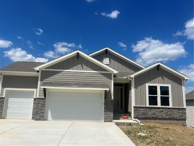 1128 SW Whitby Dr, Lees Summit, MO 64083 - craftsman-style home with stone siding, driveway, an attached garage, and board and batten siding