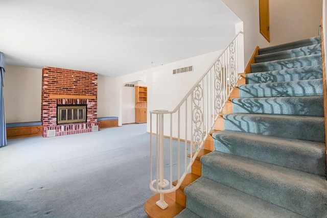 stairs with carpet floors and a fireplace