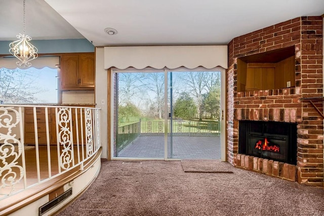 unfurnished living room featuring an inviting chandelier, a fireplace, and carpet flooring