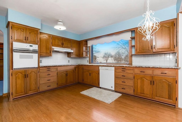 kitchen with pendant lighting, white appliances, light hardwood / wood-style floors, and decorative backsplash