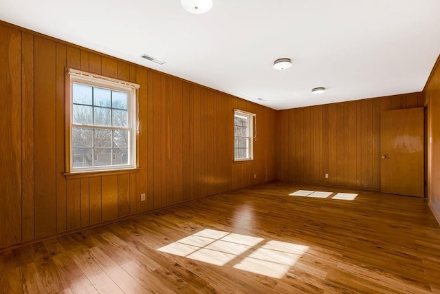 unfurnished room with wood walls and light hardwood / wood-style flooring