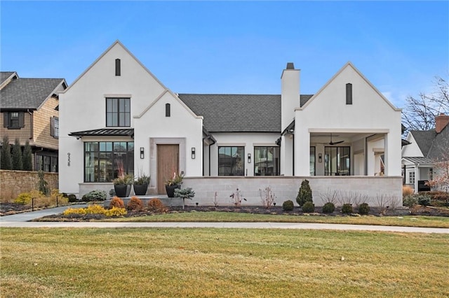 modern farmhouse with a standing seam roof, a chimney, and a front lawn